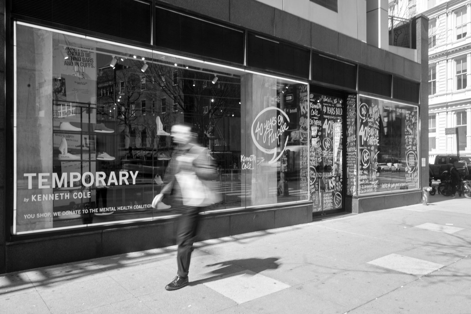 Kenneth Cole temporary storefront lettered for the 40th anniversary, a shopper rushing past